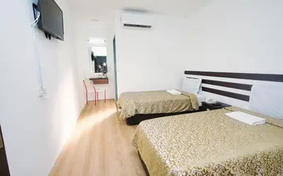 a hotel room with two beds and a television at Grand Inn Hotel - Macalister Road in George Town