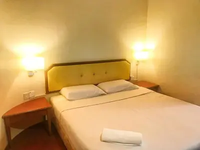 a bedroom with a large bed with two lamps on it at Hotel Sri Raub in Raub