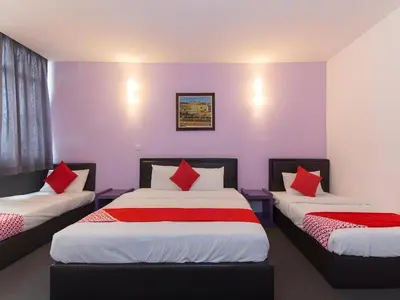 two beds in a room with purple walls and red pillows at Hotel O Marvelton Hotel in Butterworth