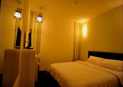 a bedroom with a bed and two lights on the wall at Hotel O Marvelton Hotel in Butterworth