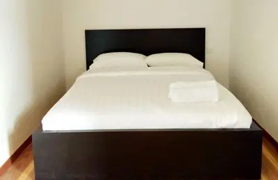 a bed with a black frame and white sheets and pillows at Petak Padin Cottage by The Pool, Kepala Batas Penang in Kepala Batas