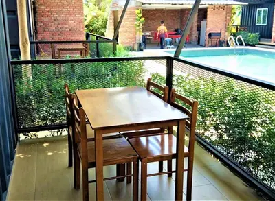 a table and chairs on a balcony with a pool at Petak Padin Cottage by The Pool, Kepala Batas Penang in Kepala Batas