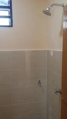 a bathroom with a shower with a tiled wall at IsMa Lumut Homestay in Lumut