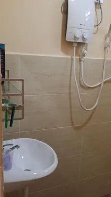 a bathroom with a white sink and a soap dispenser at IsMa Lumut Homestay in Lumut