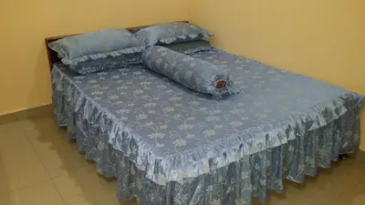 a bed with a blue comforter and pillows on it at IsMa Lumut Homestay in Lumut