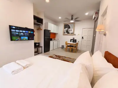 a bedroom with a white bed and a kitchen at 3 Concordia @ Gurney in George Town