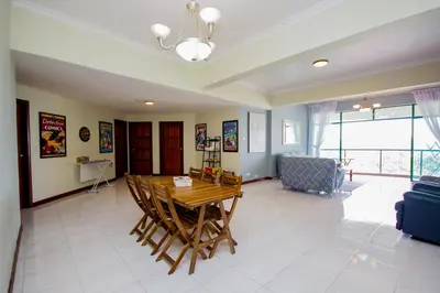 a living room with a wooden table and chairs at Fun Apartment @ Equatorial Hill Resort in Cameron Highlands