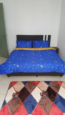a bed with a blue comforter and a rug at Ainul MarDhiah @ Cameron Highland (muslim stay) in Cameron Highlands