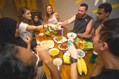 a group of people sitting around a table eating food at Traveller Bunker Hostel 1 in Cameron Highlands
