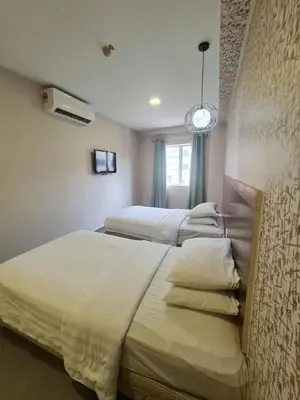 a bedroom with two beds and a clock on the wall at Hotel Bestari in Kuala Lipis