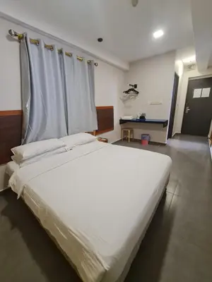 a bedroom with a large white bed with white sheets at Hotel Bestari in Kuala Lipis
