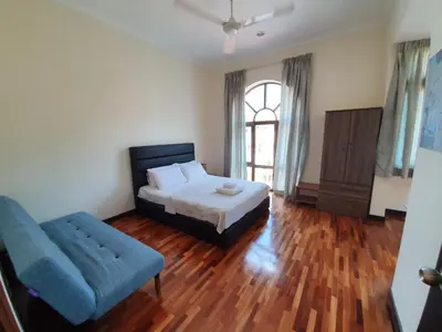 a bedroom with a bed and a blue couch at Eden Cosy Living in Batu Ferringhi
