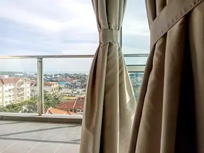 a curtain in a window with a view of a city at Sekinchan HighLevel SeaView Homestay \u9ad8\u697c \u770b\u6d77 \u9633\u53f0\u6c11\u5bbf in Sekincan