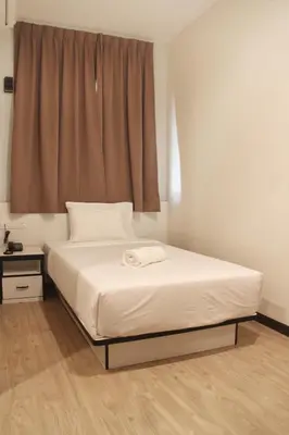 a bed in a room with a window with a white bedspread at Gergasi Inn in Ipoh