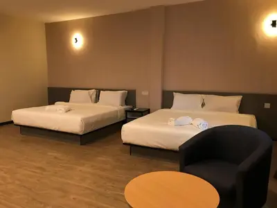a room with two beds and a chair and a table at Gergasi Inn in Ipoh