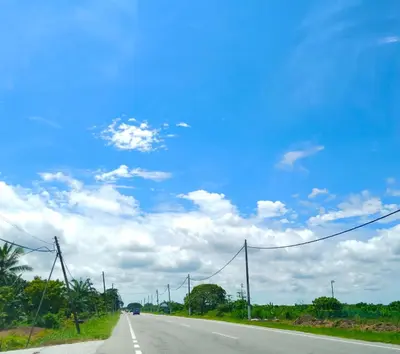 an empty road with a blue sky and clouds at Rumah Tamu Azizah in Kampong Tanjong Bayan