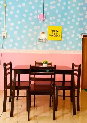 a dining room table and chairs with a sign on the wall at Rumah Tamu Azizah in Kampong Tanjong Bayan