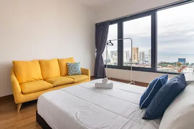 a bedroom with a large bed and a yellow couch at Tropicana 218 X Airlevate Suites in George Town