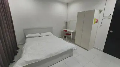 a small white bedroom with a bed and a cabinet at D'Sandra Homestay in Kulim