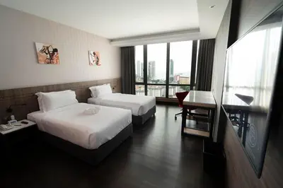 a hotel room with two beds and a desk and a window at Jazz Hotel Penang in George Town