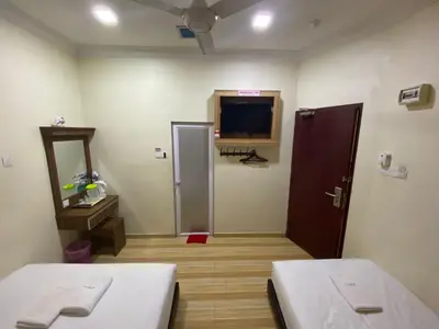 a room with two beds and a tv on the wall at Haji Saudi Hotel in Cameron Highlands
