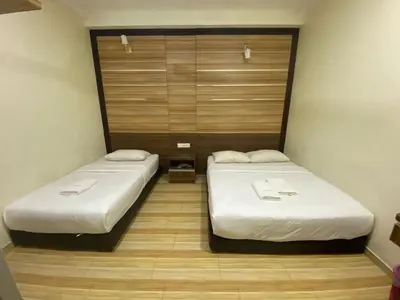 two beds in a small room with wooden floors at Haji Saudi Hotel in Cameron Highlands