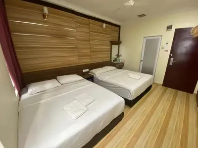 a hotel room with two beds and a wooden wall at Haji Saudi Hotel in Cameron Highlands