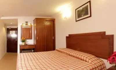 a bedroom with a bed with a checkered blanket at Jasmine Hotel in Cameron Highlands