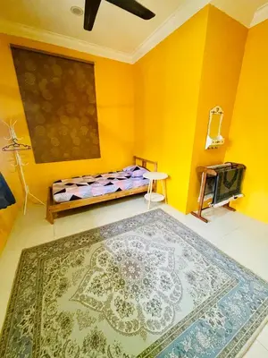 a yellow room with a bed and a rug at D Corner Islam Homestay in Kuala Kangsar