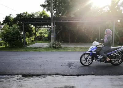 a woman riding a motorcycle with a dog on the back at Rumah Citta Homestay Tambun Ipoh in Ipoh