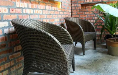 two wicker chairs sitting next to a brick wall at The Happy 8 Retreat in Ipoh