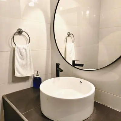 a bathroom with a white sink and a mirror at Boulder Valley in Batu Ferringhi