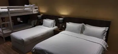 a hotel room with two beds and a chair at Boulder Valley in Batu Ferringhi