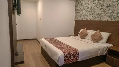 a bedroom with a bed with a large white bedspread at Highlanders Hotel in Cameron Highlands