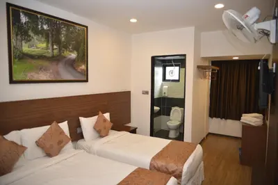 a hotel room with two beds and a bathroom at Highlanders Hotel in Cameron Highlands