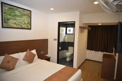 a bedroom with a bed and a bathroom with a shower at Highlanders Hotel in Cameron Highlands