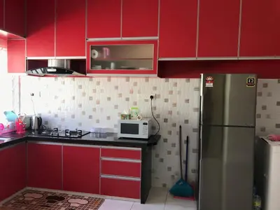 a kitchen with red cabinets and a stainless steel refrigerator at Safwa Homestay Bagan Serai in Bagan Serai