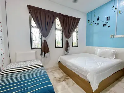 two beds in a room with blue walls and windows at Ks Homestay in Taiping