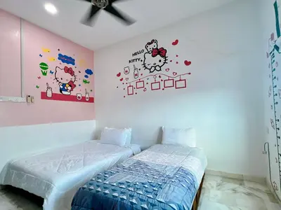 a bedroom with two beds and a wall with hello kitty stickers at Ks Homestay in Taiping