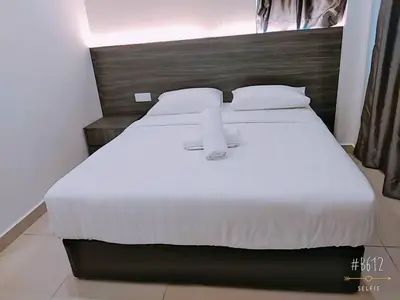 a bedroom with a large white bed with a wooden headboard at KU-3 HOTEL in Tapah