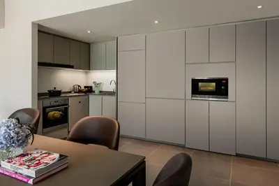 a kitchen with white cabinets and a table with chairs at Ascott Gurney Penang in George Town