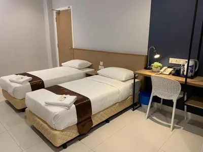 two beds in a hotel room with a desk and a chair at MD Boutique Hotel in Kampar