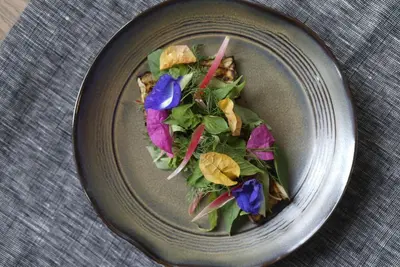 a gray plate with a salad on a table at Victoria Garden Hotel in George Town