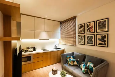 a living room with a couch and a kitchen at Macalister Hotel Managed by The Ascott Limited in George Town