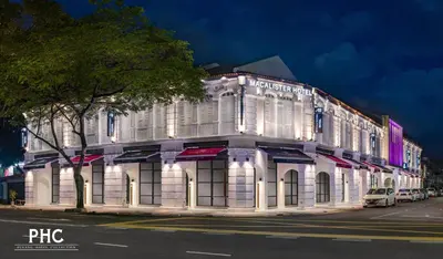 a white building on a city street at night at Macalister Hotel Managed by The Ascott Limited in George Town