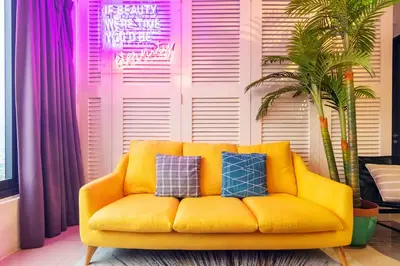 a yellow couch in a living room with purple curtains at Tropicana 218 Macalister X Airlevate Suites in George Town