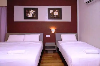 two beds in a hotel room with white sheets at Ipoh Boutique Hotel in Ipoh