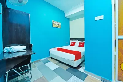 a blue room with a bed and a desk at Hotel O Bamboo Inn in Batu Ferringhi