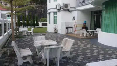 a patio with white chairs and tables and a building at 6, Persiaran Tanjung Bunga 3 in Batu Ferringhi