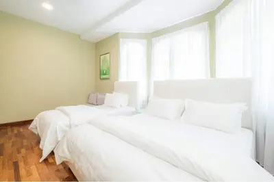a room with three beds with white sheets and a window at 6, Persiaran Tanjung Bunga 3 in Batu Ferringhi